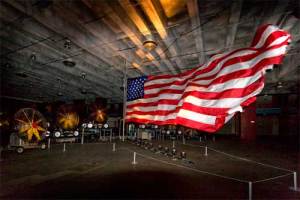 Fans blow the torn stripes of a large flag. (moca.org)