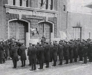 Firemen salute as a plaque honoring George Nigro is placed on the firehouse where he served