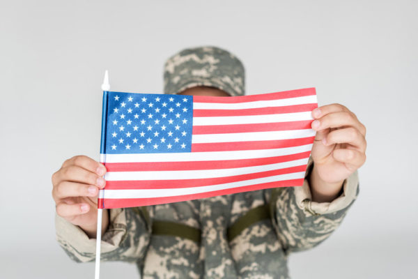 Soldier holding an American Flag obscuring his face