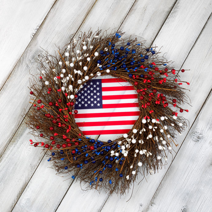 Wreath decorated for Veterans Day with USA flag inside on rustic white wooden boards.